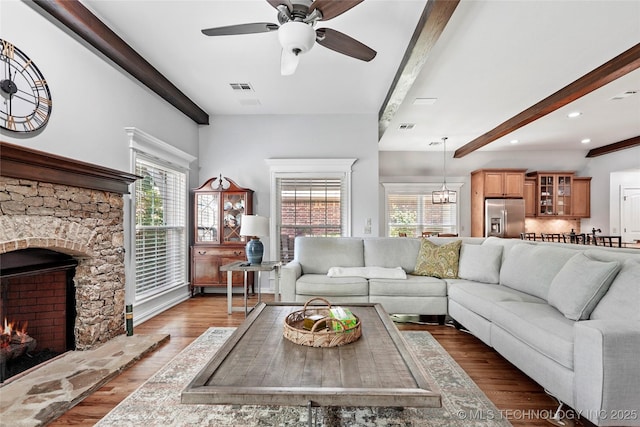 10935 S 77th Pl, Tulsa, OK 74133 - living area featuring beam ceiling, plenty of natural light, ceiling fan, wood finished floors, and a stone fireplace