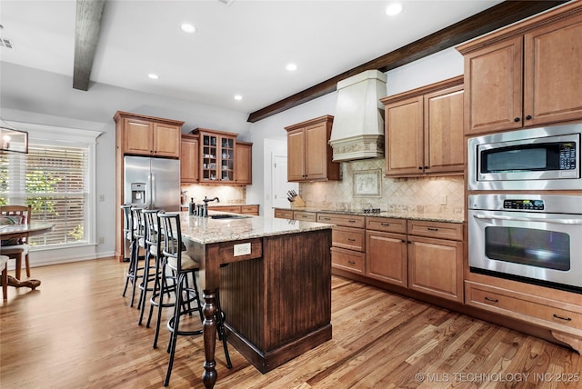 10935 S 77th Pl, Tulsa, OK 74133 - kitchen with stainless steel appliances, premium range hood, beam ceiling, a sink, and light wood-style floors