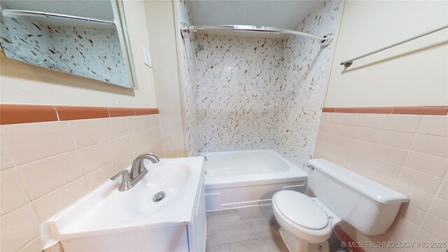 105 S B, Davis, OK 73030 - bathroom with tile walls, toilet, vanity, shower / bath combination, and wainscoting
