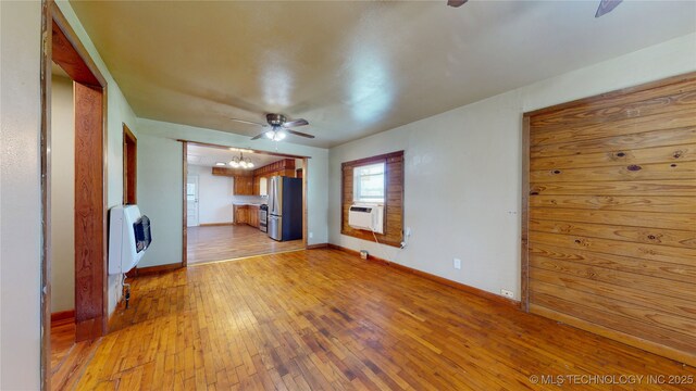 105 S B, Davis, OK 73030 - unfurnished living room featuring a chandelier, a ceiling fan, light wood-style flooring, heating unit, and baseboards