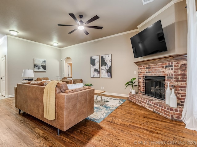 5909 E 139th St, Collinsville, OK 74021 - living area featuring arched walkways, wood finished floors, a ceiling fan, crown molding, and a brick fireplace