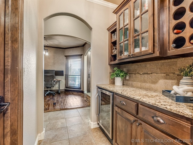 5909 E 139th St, Collinsville, OK 74021 - kitchen featuring wine cooler, ornamental molding, arched walkways, light tile patterned floors, and baseboards