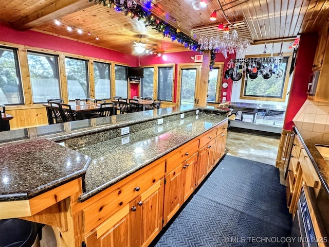 20965 W 921st Rd, Cookson, OK 74427 - kitchen with wooden ceiling, ceiling fan, brown cabinets, dark stone countertops, and rail lighting