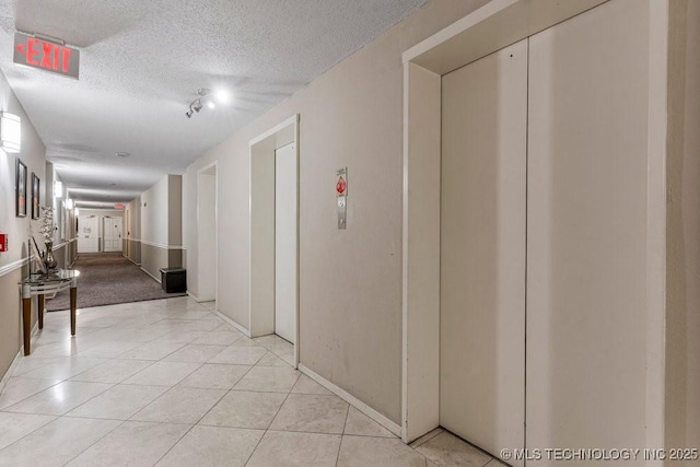 1502 S Boulder Ave Unit 16Cd, Tulsa, OK 74119 - hallway featuring elevator, a textured ceiling, light tile patterned floors, and baseboards