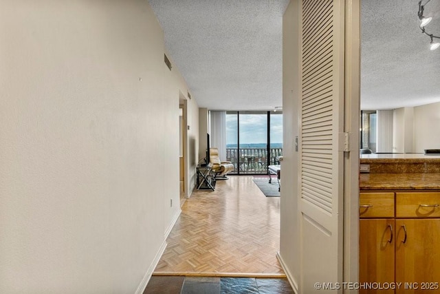 1502 S Boulder Ave Unit 16Cd, Tulsa, OK 74119 - hallway featuring a textured ceiling, baseboards, and a wall of windows