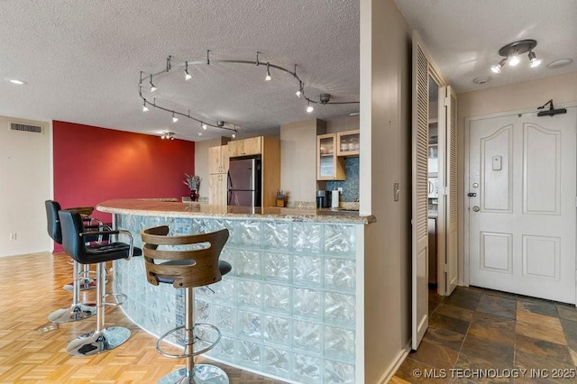 1502 S Boulder Ave Unit 16Cd, Tulsa, OK 74119 - kitchen with freestanding refrigerator, track lighting, a peninsula, a textured ceiling, and light countertops