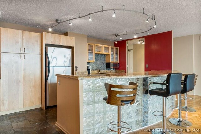 1502 S Boulder Ave Unit 16Cd, Tulsa, OK 74119 - kitchen featuring stainless steel appliances, glass insert cabinets, baseboards, rail lighting, and a textured ceiling
