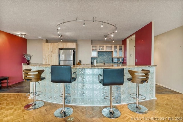 1502 S Boulder Ave Unit 16Cd, Tulsa, OK 74119 - kitchen featuring appliances with stainless steel finishes, a kitchen breakfast bar, glass insert cabinets, baseboards, and track lighting