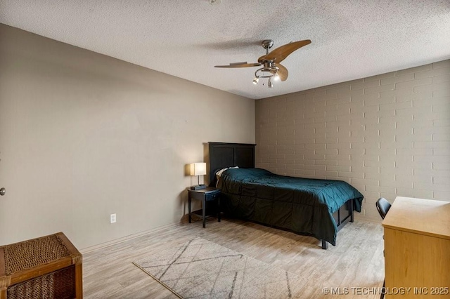 1502 S Boulder Ave Unit 16Cd, Tulsa, OK 74119 - bedroom with wood finished floors, a ceiling fan, a textured ceiling, and concrete block wall