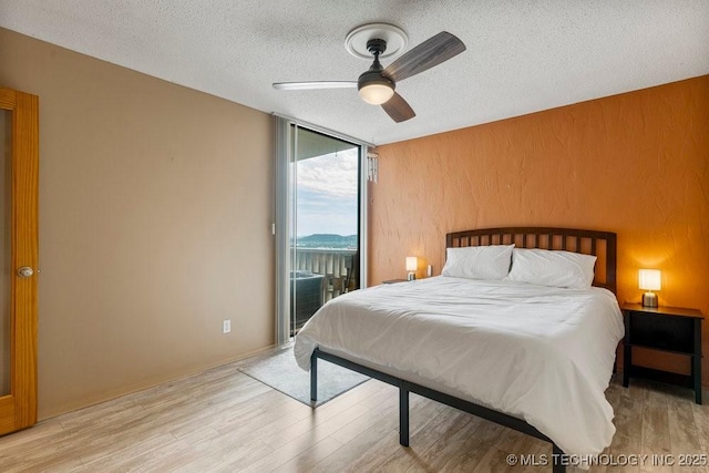 1502 S Boulder Ave Unit 16Cd, Tulsa, OK 74119 - bedroom with access to outside, expansive windows, a textured ceiling, wood finished floors, and a ceiling fan