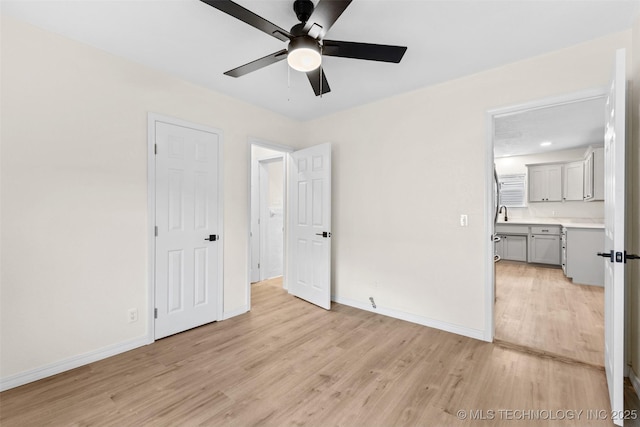 524 W 18th, Ada, OK 74820 - unfurnished bedroom featuring light wood-type flooring, baseboards, a ceiling fan, and connected bathroom
