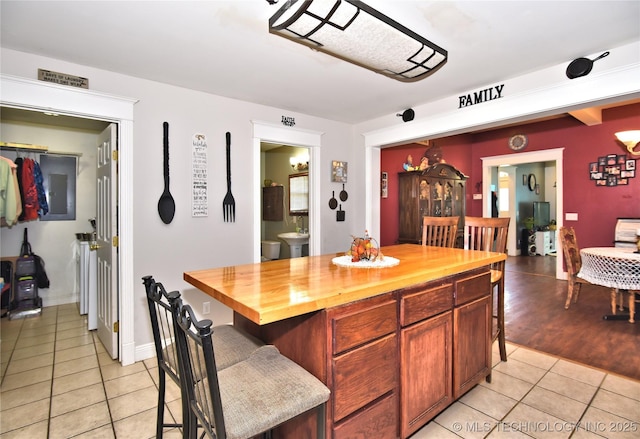208 N Vine Ave, Cleveland, OK 74020 - kitchen with butcher block counters, light tile patterned floors, a breakfast bar, and a center island