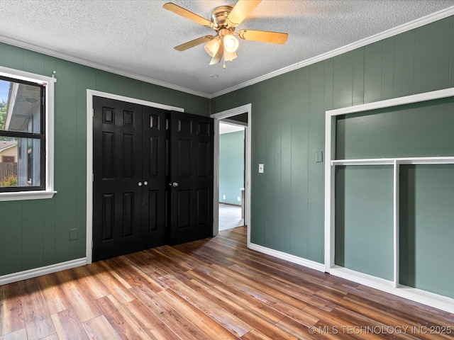 324 2019th Rd, Bartlesville, OK 74003 - unfurnished bedroom featuring wood finished floors, a closet, a textured ceiling, crown molding, and ceiling fan