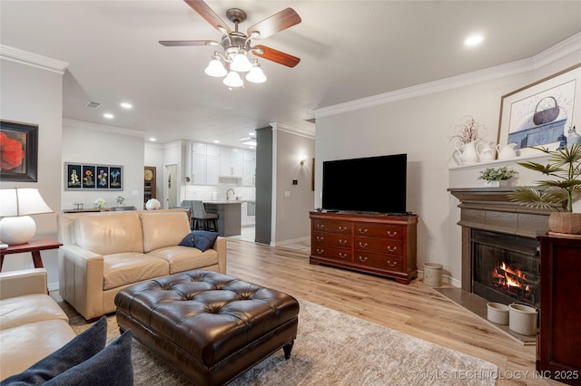 7724 S 83rd E Ave, Tulsa, OK 74133 - living area featuring crown molding, a ceiling fan, light wood-style floors, a warm lit fireplace, and recessed lighting