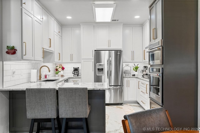7724 S 83rd E Ave, Tulsa, OK 74133 - kitchen featuring a sink, stainless steel appliances, a peninsula, light marble finish flooring, and light stone counters