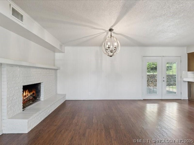 5339 S 32nd W Ave, Tulsa, OK 74107 - unfurnished living room featuring a chandelier, wood finished floors, a textured ceiling, a brick fireplace, and baseboards