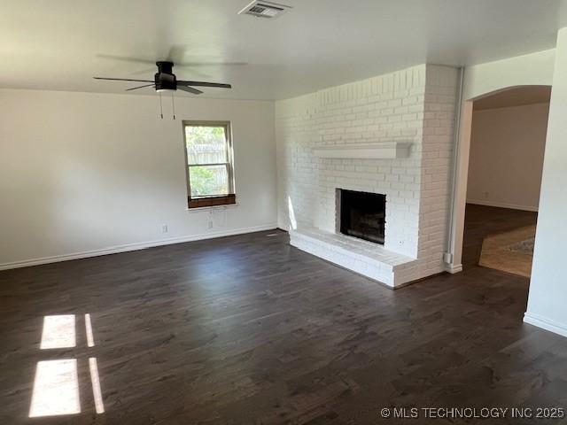 1800 N 26th St, Broken Arrow, OK 74014 - unfurnished living room featuring baseboards, ceiling fan, dark wood-style floors, arched walkways, and a fireplace