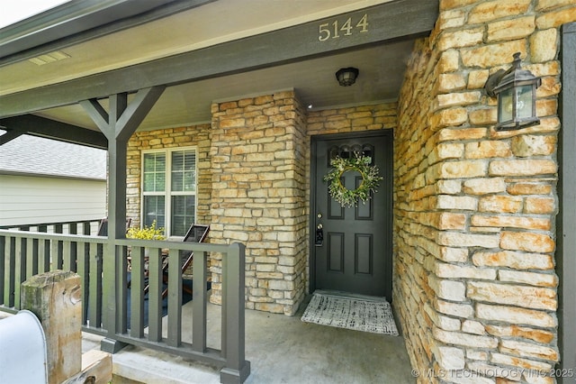 5144 S 34th W Ave, Tulsa, OK 74107 - doorway to property featuring covered porch, stone siding, and brick siding