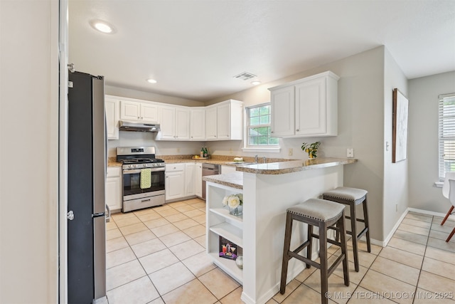 5144 S 34th W Ave, Tulsa, OK 74107 - kitchen with stainless steel appliances, under cabinet range hood, a peninsula, white cabinets, and light tile patterned floors