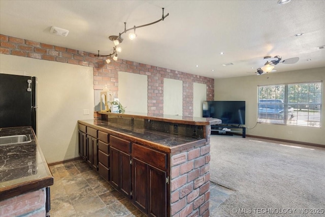 211 Meadowlark, Durant, OK 74701 - kitchen featuring freestanding refrigerator, a peninsula, dark brown cabinetry, ceiling fan, and baseboards