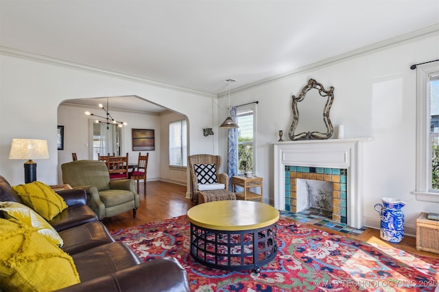 1224 S Columbia Pl, Tulsa, OK 74104 - living room with arched walkways, wood finished floors, crown molding, a chandelier, and a tile fireplace