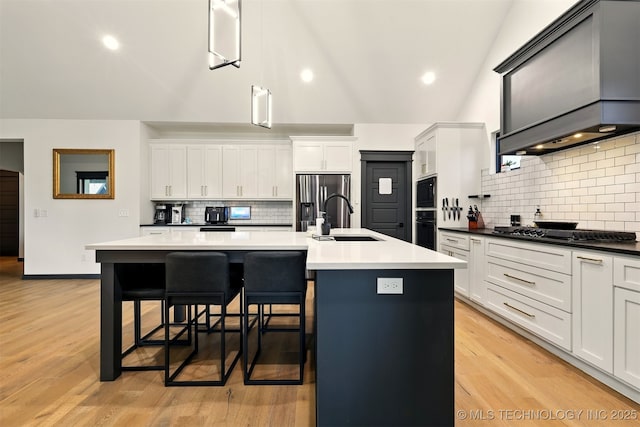 5807 E 128th St S, Bixby, OK 74008 - kitchen with black appliances, a sink, backsplash, custom range hood, and a kitchen island with sink