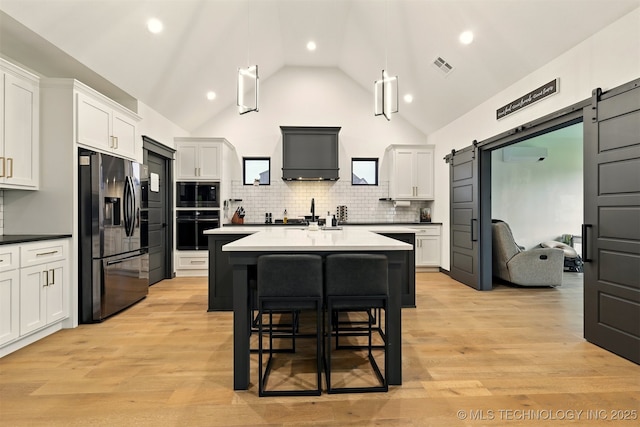5807 E 128th St S, Bixby, OK 74008 - kitchen with refrigerator with ice dispenser, black oven, a barn door, built in microwave, and a center island