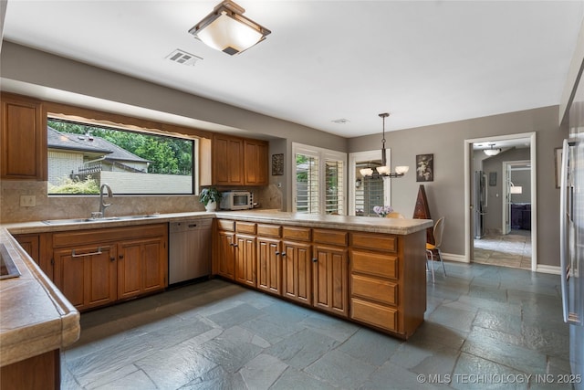 6232 S Jamestown Ave, Tulsa, OK 74136 - kitchen featuring dishwasher, a sink, a peninsula, brown cabinets, and stone tile floors