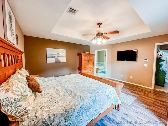 418847 E 1208th Rd, Eufaula, OK 74432 - bedroom with a tray ceiling, baseboards, wood finished floors, a ceiling fan, and ensuite bathroom