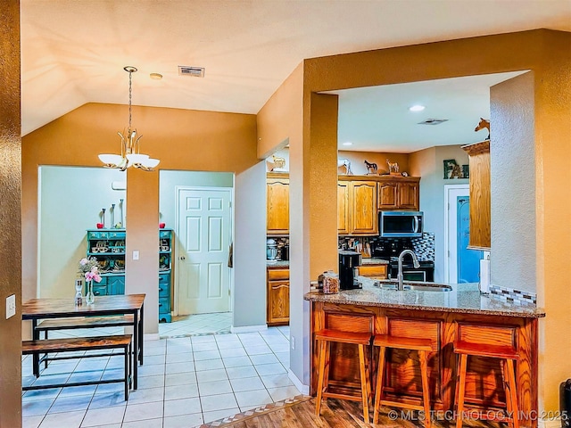 418847 E 1208th Rd, Eufaula, OK 74432 - kitchen with stainless steel microwave, brown cabinets, a sink, a chandelier, and light stone counters