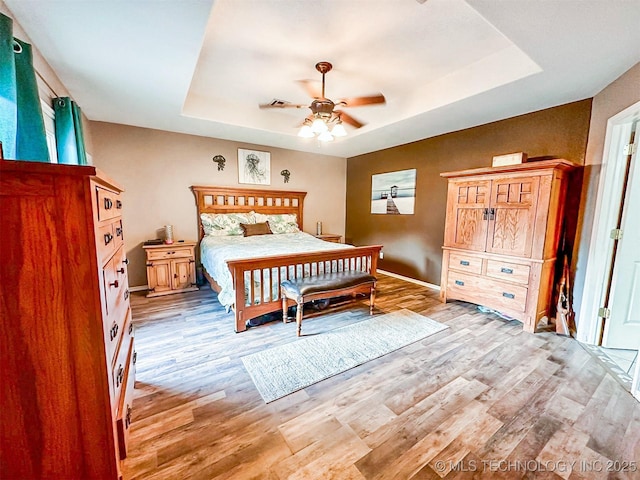 418847 E 1208th Rd, Eufaula, OK 74432 - bedroom featuring a raised ceiling, light wood-style flooring, baseboards, and a ceiling fan