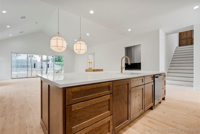3917 S Madison Ave, Tulsa, OK 74105 - kitchen with a sink, light wood-type flooring, open floor plan, brown cabinets, and high vaulted ceiling