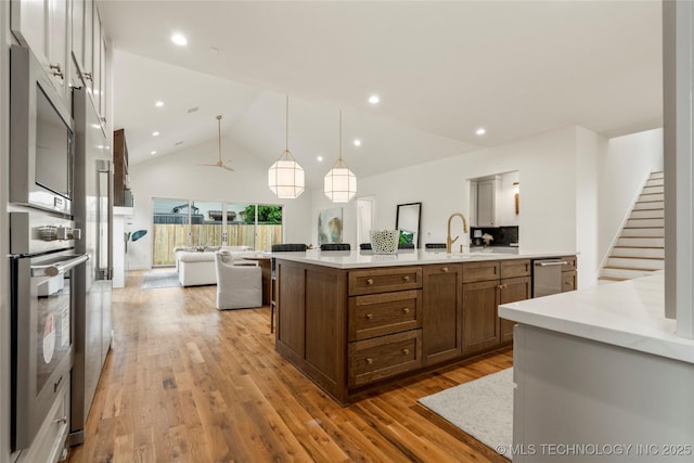 3917 S Madison Ave, Tulsa, OK 74105 - kitchen with stainless steel appliances, open floor plan, light wood-style flooring, light countertops, and ceiling fan