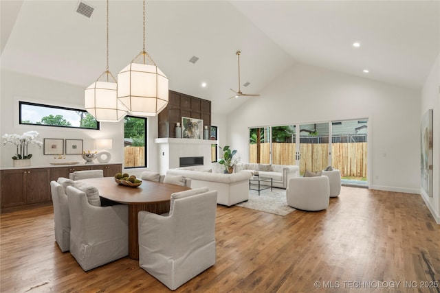 3917 S Madison Ave, Tulsa, OK 74105 - dining area featuring high vaulted ceiling, a fireplace, wood finished floors, plenty of natural light, and a ceiling fan