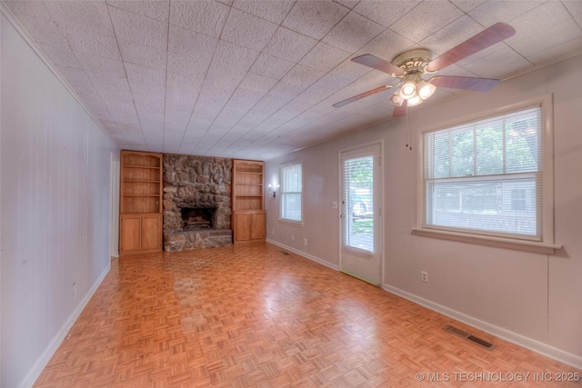 234 E Freeport St, Broken Arrow, OK 74012 - unfurnished living room with built in shelves, baseboards, a stone fireplace, and ceiling fan