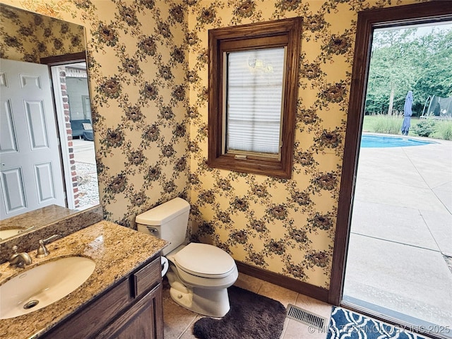 4224 S 69th W Ave, Tulsa, OK 74107 - half bath with baseboards, toilet, vanity, tile patterned flooring, and wallpapered walls
