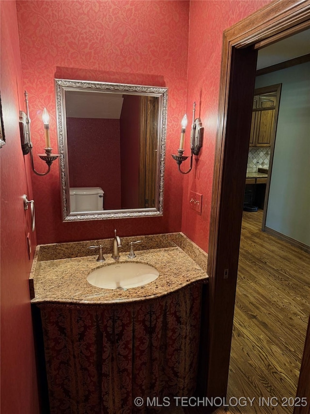 4224 S 69th W Ave, Tulsa, OK 74107 - half bathroom with vanity, wood finished floors, toilet, and wallpapered walls
