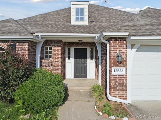 12523 S Cedar Pl, Jenks, OK 74037 - doorway to property featuring a shingled roof, brick siding, and a garage