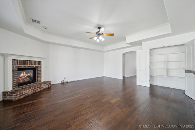 12523 S Cedar Pl, Jenks, OK 74037 - unfurnished living room featuring a tray ceiling, arched walkways, ceiling fan, crown molding, and dark wood-type flooring