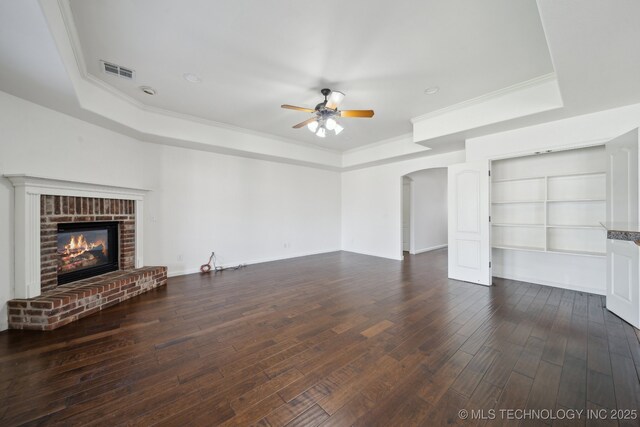 12523 S Cedar Pl, Jenks, OK 74037 - unfurnished living room featuring a tray ceiling, a ceiling fan, arched walkways, ornamental molding, and dark wood finished floors