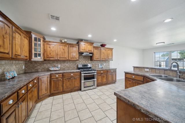 12523 S Cedar Pl, Jenks, OK 74037 - kitchen featuring range with two ovens, under cabinet range hood, brown cabinetry, backsplash, and dark countertops