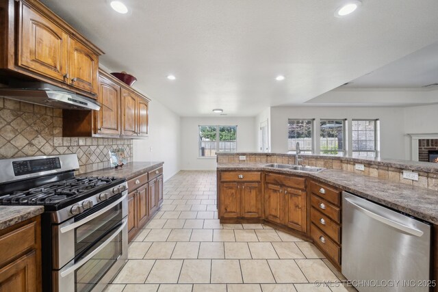 12523 S Cedar Pl, Jenks, OK 74037 - kitchen featuring appliances with stainless steel finishes, under cabinet range hood, tasteful backsplash, recessed lighting, and brown cabinets