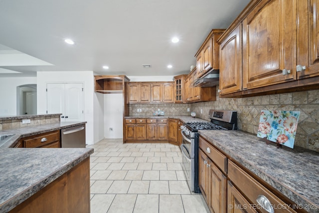 12523 S Cedar Pl, Jenks, OK 74037 - kitchen featuring appliances with stainless steel finishes, brown cabinetry, under cabinet range hood, tasteful backsplash, and arched walkways