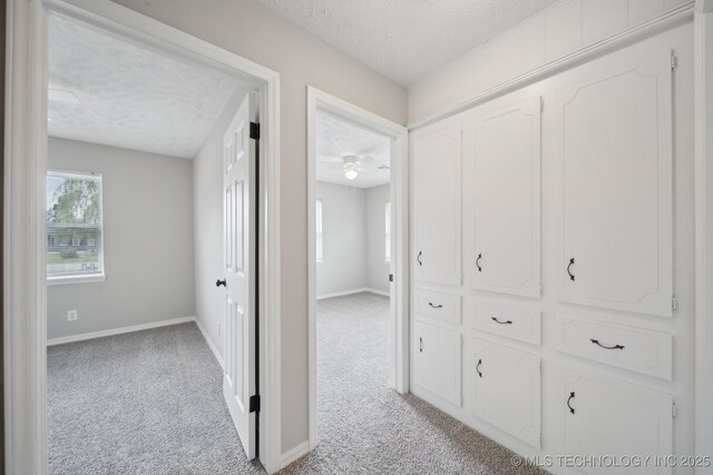 128 Suburban Ln, Inola, OK 74036 - corridor featuring a textured ceiling, light colored carpet, and baseboards