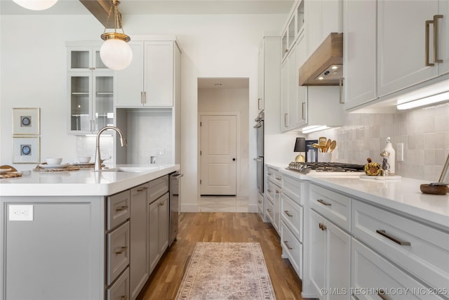 2338 E 134th St S, Bixby, OK 74008 - kitchen featuring wall chimney exhaust hood, stainless steel appliances, tasteful backsplash, light wood finished floors, and light countertops