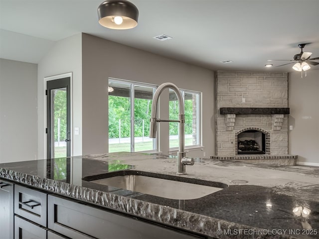 13155 S 105th E Ave, Bixby, OK 74008 - kitchen featuring a sink, dark stone counters, a fireplace, and a ceiling fan