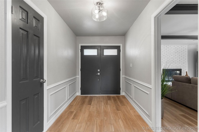 7532 E 55th Pl, Tulsa, OK 74145 - foyer featuring a decorative wall, light wood-type flooring, a wainscoted wall, and a fireplace