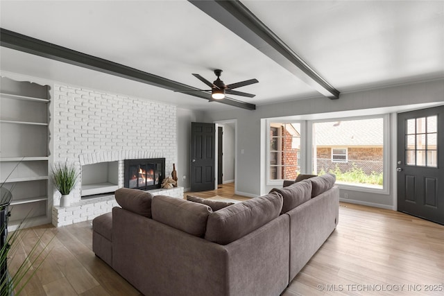 7532 E 55th Pl, Tulsa, OK 74145 - living area featuring light wood-style flooring, a brick fireplace, baseboards, ceiling fan, and beam ceiling