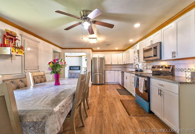 7008 S Hwy 28, Chelsea, OK 74016 - kitchen with appliances with stainless steel finishes, light wood-type flooring, white cabinets, a sink, and ornamental molding