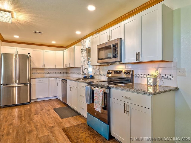 7008 S Hwy 28, Chelsea, OK 74016 - kitchen with stainless steel appliances, a sink, light wood-style floors, dark stone counters, and tasteful backsplash
